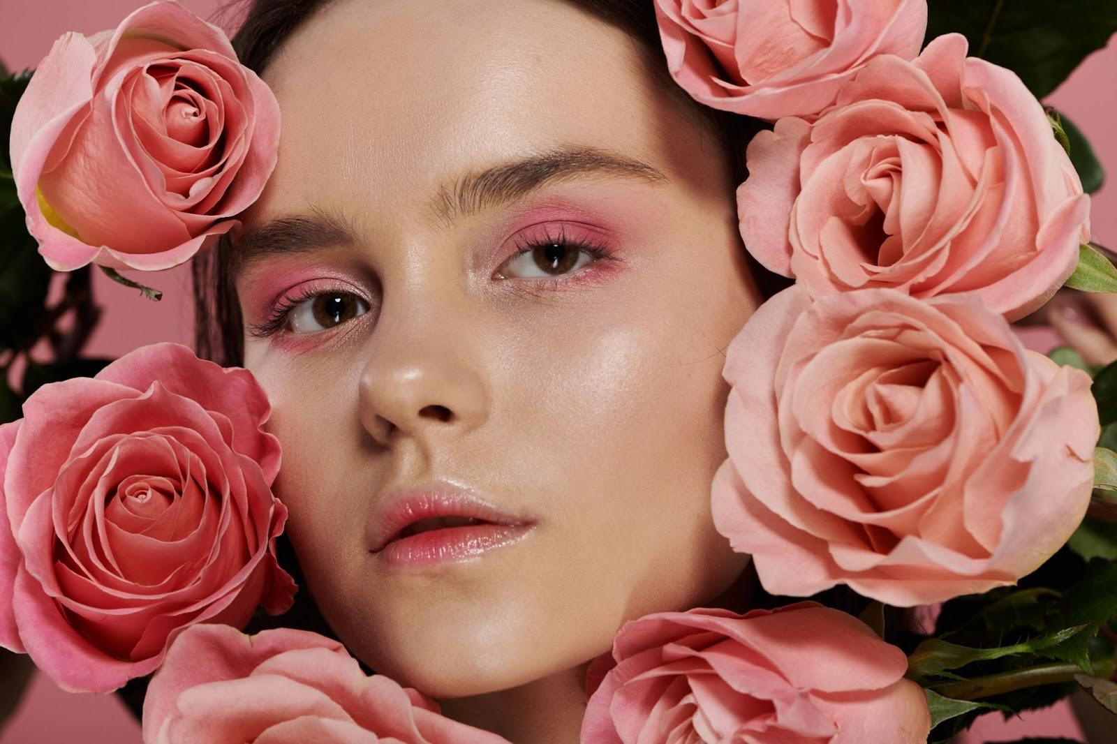 A woman with pink eyeshadow surrounded by pink roses