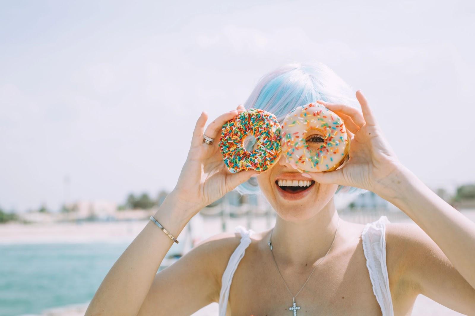 Portrait of a young woman covering eyes with donuts