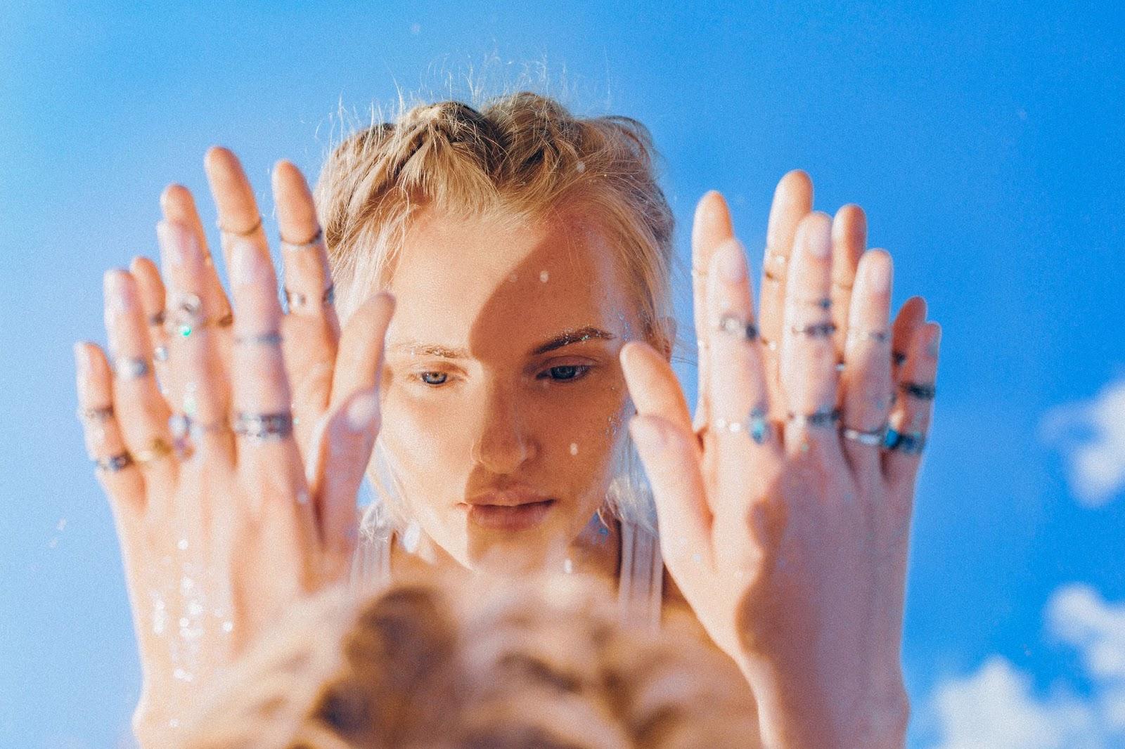 Reflection of a trendy woman in a mirror with blue sky as background